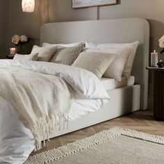 a bed with white sheets and pillows in a bedroom