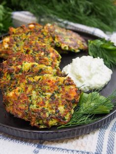 some food is on a black plate with greens and cottage cheese next to it,