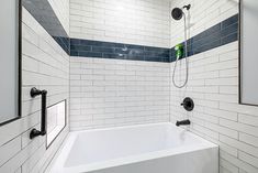 a white bath tub sitting next to a shower faucet in a bathroom under a window