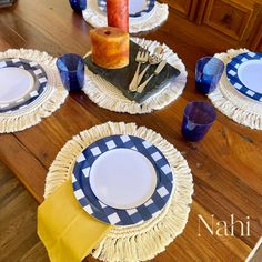 the table is set with blue and white plates, yellow napkins, and a candle