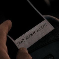 a person holding a cell phone with a label on it that says, don't believe he lies