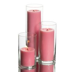 three pink candles sitting next to each other in glass vases on a white background