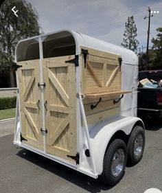 a white trailer with wooden doors is parked in a parking lot