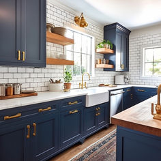 a kitchen with blue cabinets and white subway backsplash, gold pulls on the faucets