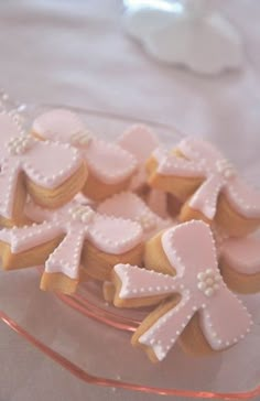 some cookies that are on a glass platter with pink icing and white frosting