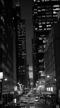 black and white photograph of city street at night with skyscrapers lit up in the background