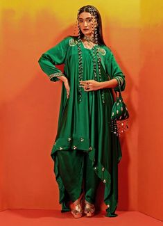 Presenting the Green Embroidered Asymmetric Kurta with Dhoti, crafted from luxurious vegan satin, that exudes elegance and modern charm. The rich green kurta is beautifully adorned with intricate hand embroidery, showcasing delicate gold sequins, zari work, and pearl bead detailing. Paired with stylish dhoti pants, this set is an ideal Indo-western choice for Mehndi, weddings, or festive occasions, this outfit is designed to make a lasting impression. Composition : Top, Bottom - Vegan Satin Care: Dry Clean Only and Vacuum Storage This product can be customized for sleeves, blouse length and neckline Delivery : 2-4 weeks as the product is hand crafted. Check Size Guide or choose MySize for free customisation (All Sizes above XL can be made at 15% additional cost) For more information and si Kurta With Dhoti, Stylish Drapes, Asymmetric Kurta, Dhoti Pants, Vacuum Storage, Indian Wedding Wear, Sleeves Blouse, Zari Work, Rich Green