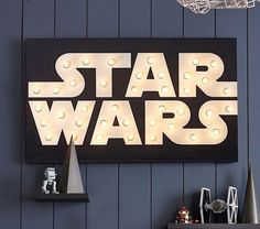 a star wars light up sign hanging on the side of a wall next to a shelf