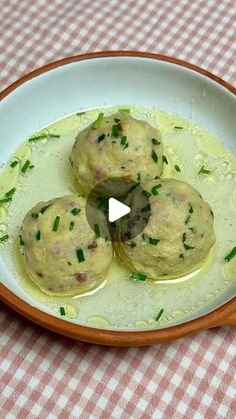 three dumplings are sitting in a bowl on a checkered tablecloth with green sauce