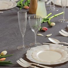 the table is set with glasses, plates and utensils for an elegant dinner