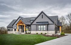 a large gray house sitting on top of a lush green field