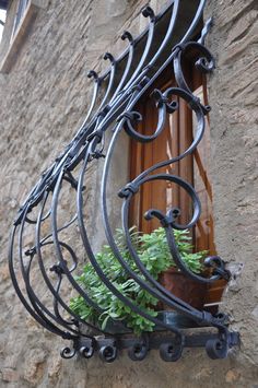 an iron balcony railing with potted plants on the ledge and window sill below