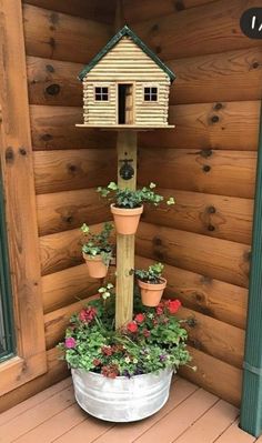 a potted planter filled with flowers next to a birdhouse on a porch