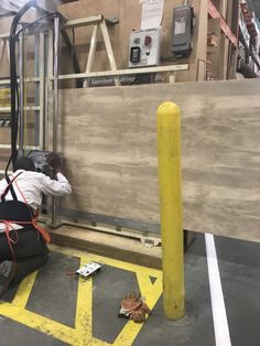 a man working on a piece of wood in a building with construction equipment around him