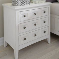 a white dresser sitting next to a bed with pillows on top of it's sides