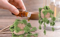 a hand is pouring oil on some crocheted plants