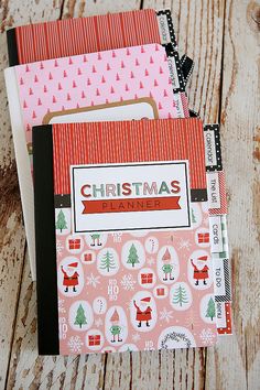 three notebooks with christmas designs on them sitting next to each other in front of a wooden table