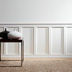 two black and white vases sitting on a table in front of a paneled wall