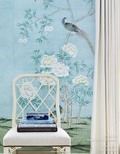 a white chair sitting in front of a blue wall with flowers and birds on it