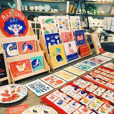 there are many paintings and cards on display at this market stall, including one for the children's art project