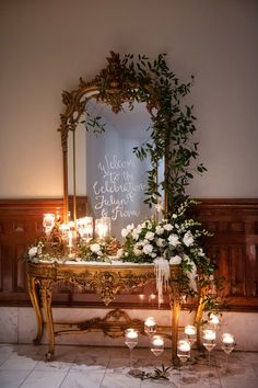 a table with candles and flowers on it in front of a mirror that says welcome celebration