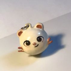 a small white cat figurine sitting on top of a table next to a keychain