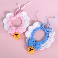 two crocheted baby bibs hanging on a pink background, one is blue and the other is white