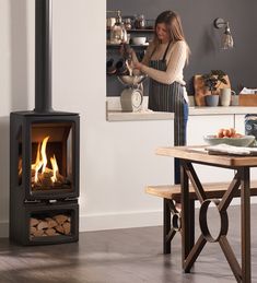 a woman standing in front of a wood stove