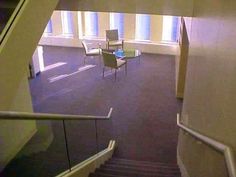 an empty room with chairs and stairs leading to the second floor, in front of two windows