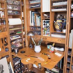 a wooden desk surrounded by shelves filled with art supplies