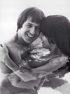 a man and woman are smiling in the water while holding each other's head