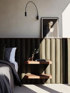 a bedroom with a bed, nightstand and side table in front of a window that has vertical blinds on the wall