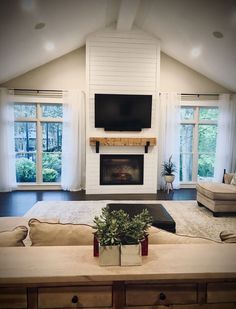 a living room with couches, fireplace and television in the middle of the room