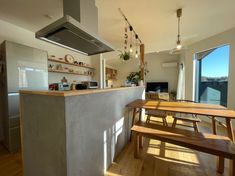 a kitchen with an island and wooden benches in front of the counter top, along with open windows