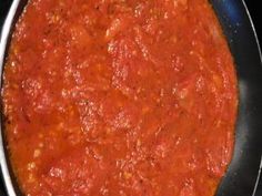 a pan filled with red sauce on top of a stove burner, ready to be cooked