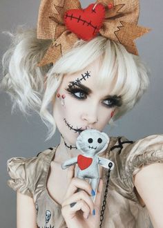 a woman with white hair and makeup holding a teddy bear