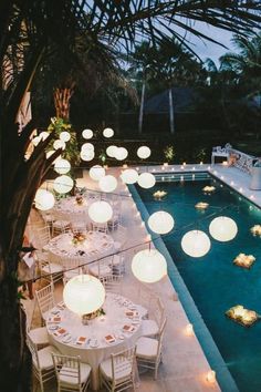 an instagramted photo with tables and chairs next to a swimming pool at night