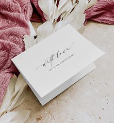 a white card with the word welcome on it next to some pink and white flowers