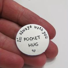 a hand holding a small silver charm that says, i'm always with you in pocket hug