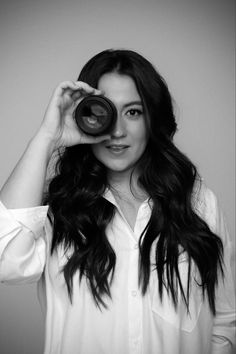 black and white photograph of a woman with long hair holding up a camera to her face