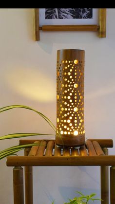 a lamp sitting on top of a wooden table next to a plant in a pot