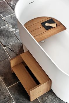 a white bath tub sitting on top of a tiled floor next to a wooden drawer