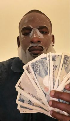 a man holding money in his hands and wearing a bandaged face mask on top of it