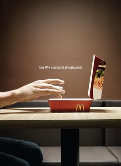 a person sitting at a table with a book in front of them and a mcdonald's box on their lap