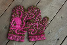 a pair of pink and brown mittens sitting on top of a wooden floor