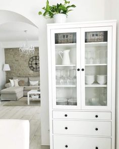 a white china cabinet with glass doors and black handles in a clean living room area