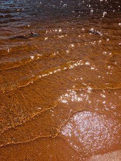 the water is brown and there are waves coming in from the shore on the beach