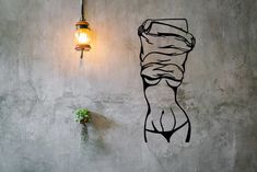 a wall with a drawing of a woman's torso on it and a light hanging from the ceiling