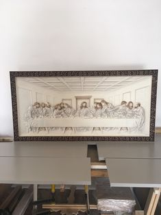 the last supper framed in wood on top of a workbench with tools nearby