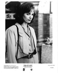 a black and white photo of a woman in a suit with a handbag on her shoulder